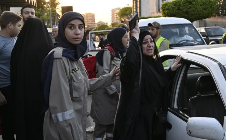 Lebanese civil defence member comforts a woman who arrived in Beirut after fleeing the south over fears of attack from Israel/EPA