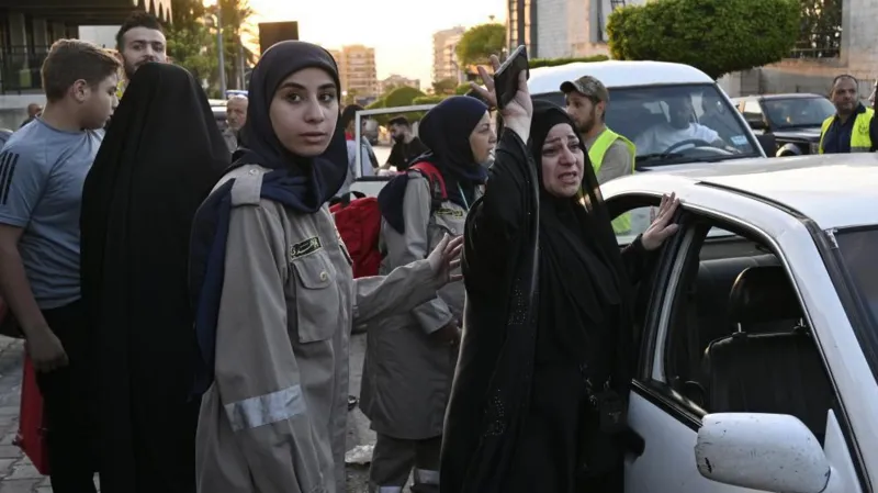 Lebanese civil defence member comforts a woman who arrived in Beirut after fleeing the south over fears of attack from Israel/EPA